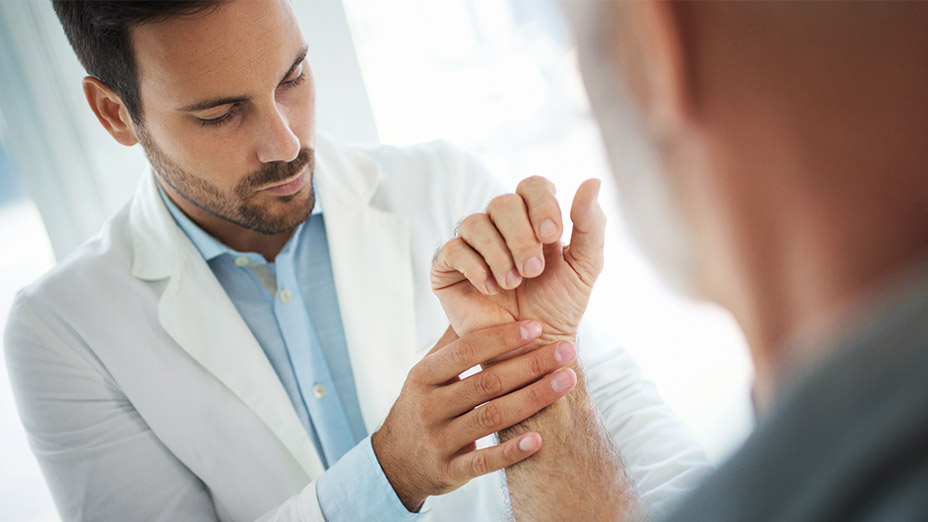 Arzt behandelt Mann mit Rheuma an der Hand Arzt behandelt Mann mit Rheuma an der Hand