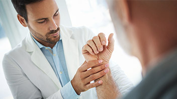 Arzt behandelt Mann mit Rheuma an der Hand