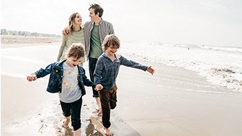 Familie mit Versicherungsschutz im Ausland am Strand