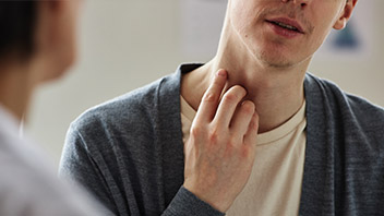 Mann fasst sich an den Hals