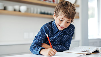 Schulkind am Schreibtisch mit Stift