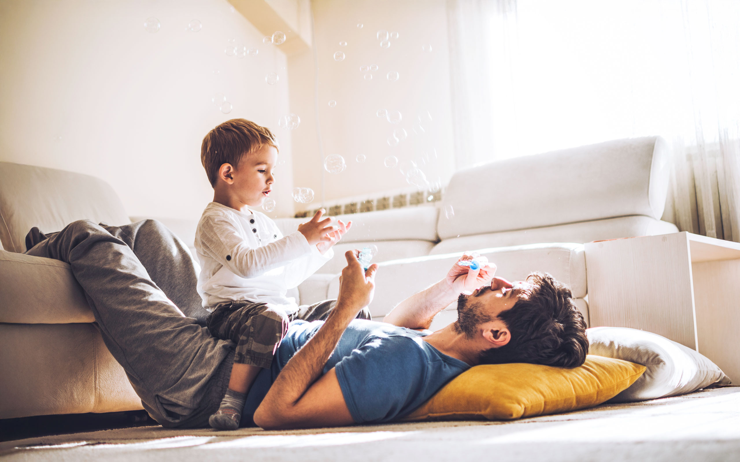 Papa und Sohn toben neben dem Sofa