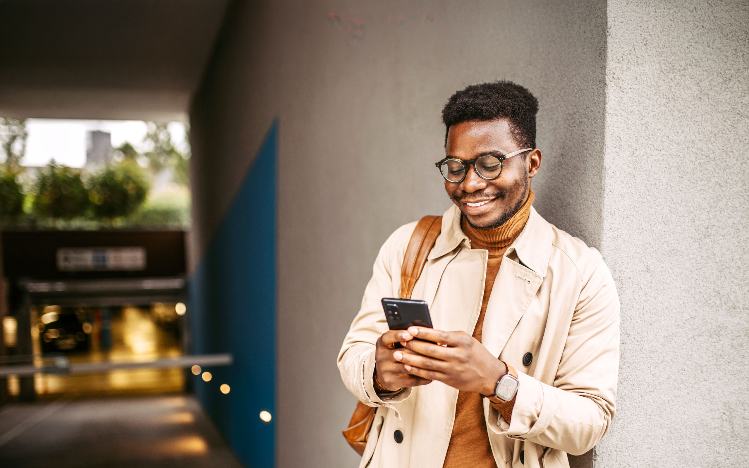 Mann mit Brille schaut lächelnd aufs Handy