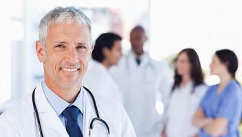 Grauhaariger Arzt lächelt in die Kamera