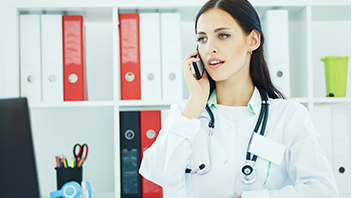Braunhaarige Ärztin im Kittel telefoniert