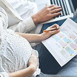 Pärchen auf der Couch mit Laptop und recherchiert nach Elterngeld auf der HEK Website
