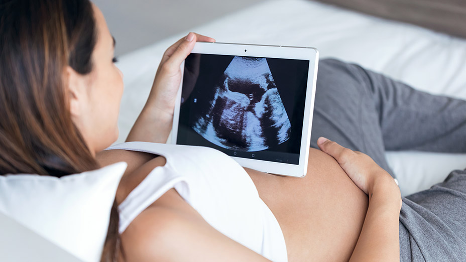 familienkonzept-schwangerschaftsvorsorge-gr Schwangere Frau auf dem Bett mit Ultraschall Bild