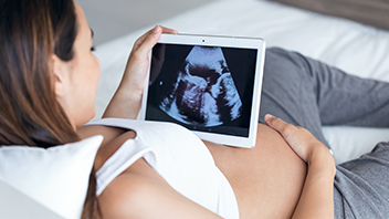 Schwangere Frau auf dem Bett mit Ultraschall Bild