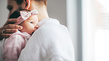 Papa mit neugeborenem Babymädchen auf dem Arm
