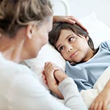 Frau sitzt am Bett ihres Kinder
