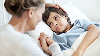 Frau sitzt am Bett ihres Kinder