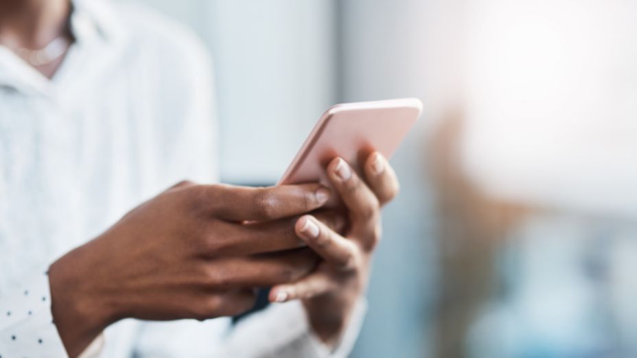 Eine Frau hält ein Handy, welches in der Farbe rosa ist.