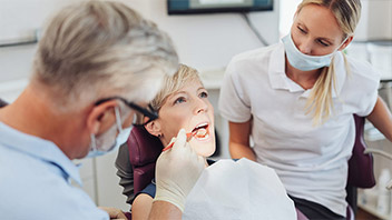 Frau bei zahnärztlicher Behandlung mit geöffnetem Mund