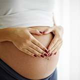 Schwangere Frau mit Händen auf dem Babybauch