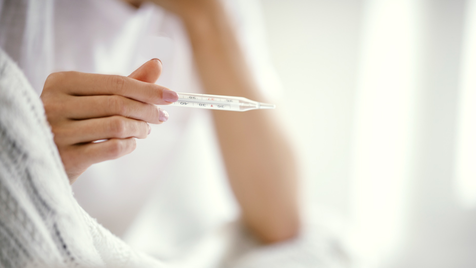 Frau mit Fieberthermometer in der Hand