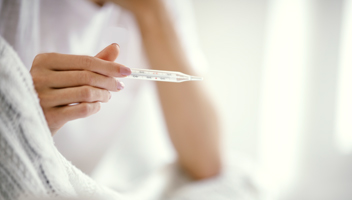 Frau mit Fieberthermometer in der Hand