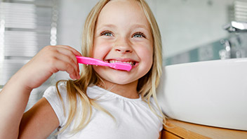 Blondes Mädchen beim Zähne putzen als Zahnvorsorge